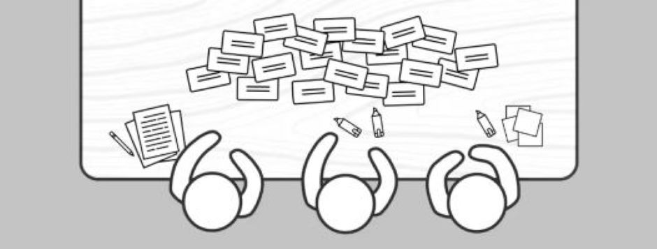 Many note cards with writing on them spread across a table. There are also supplies like pencils and paper for taking notes on the tale. Three people are in front of the table, too.